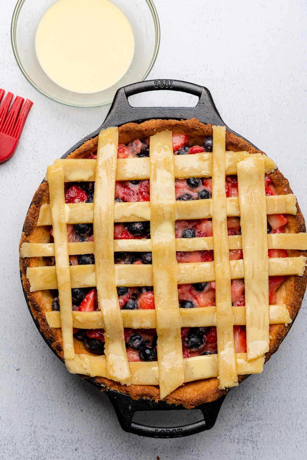 raw lattice design on a pie in a cast iron brushed with an egg wash