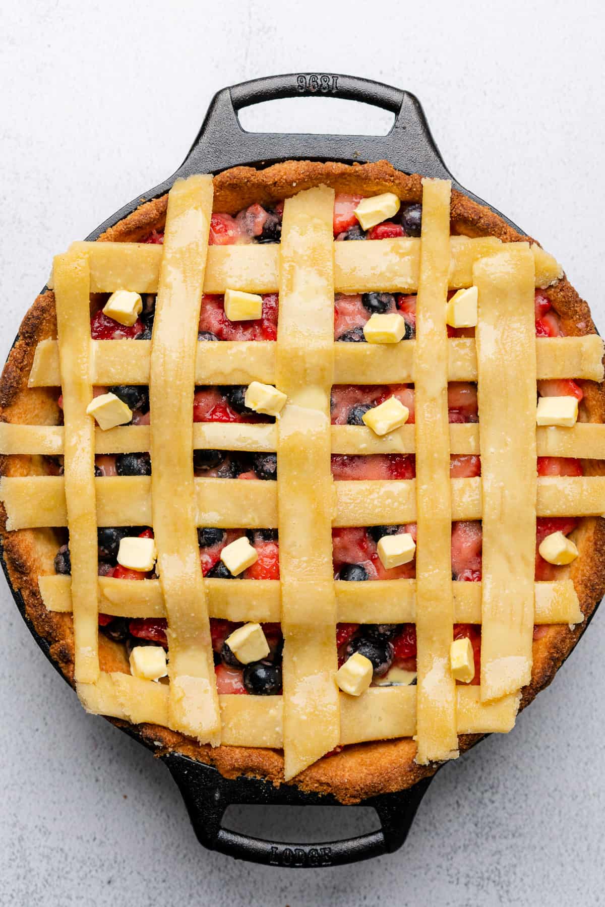 raw lattice strips on a pie with pats of butter between the shapes