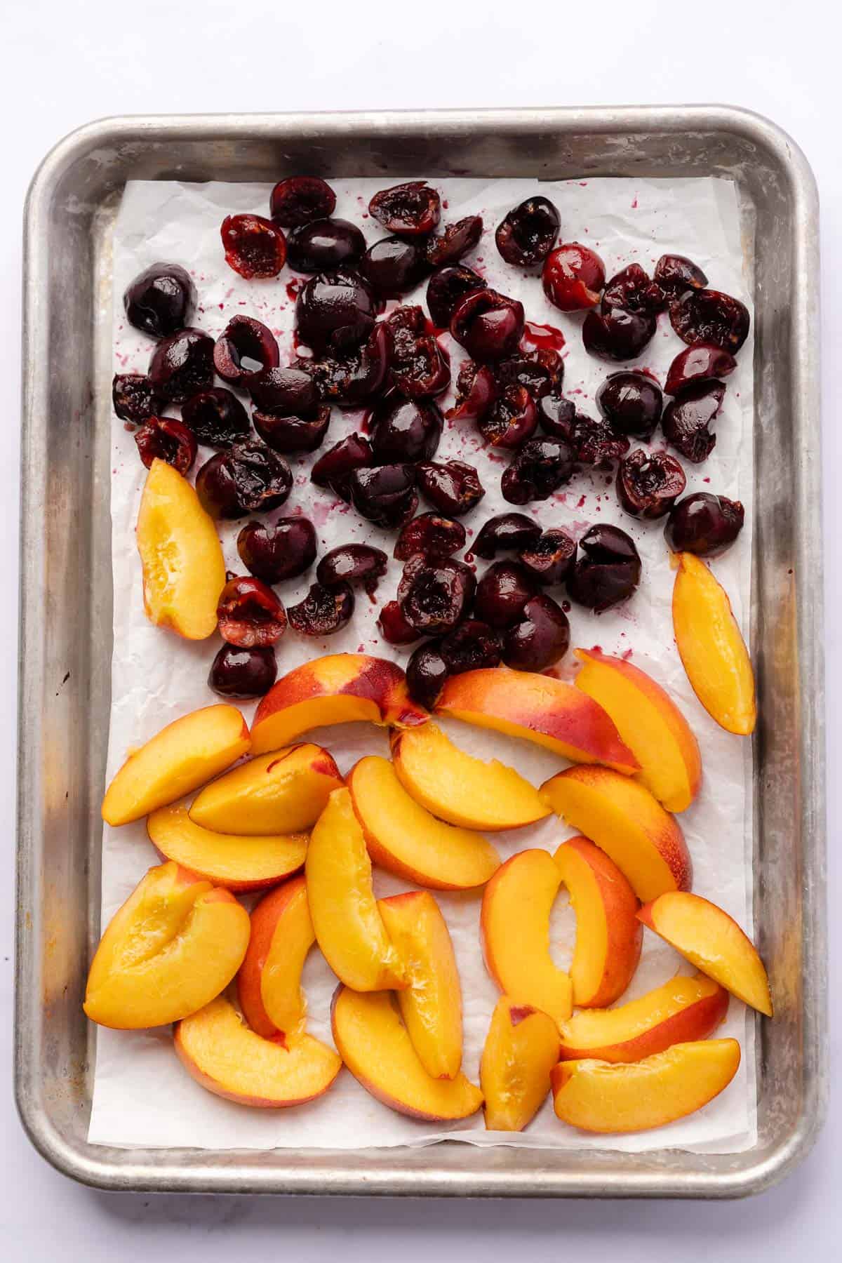 nectarines and cherries on a baking sheet with white parchment paper