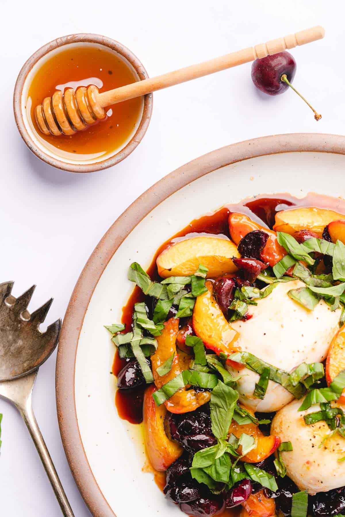 flat lay shot of burrata cheese with basil, baked nectarines and cherries with honey and balsamic