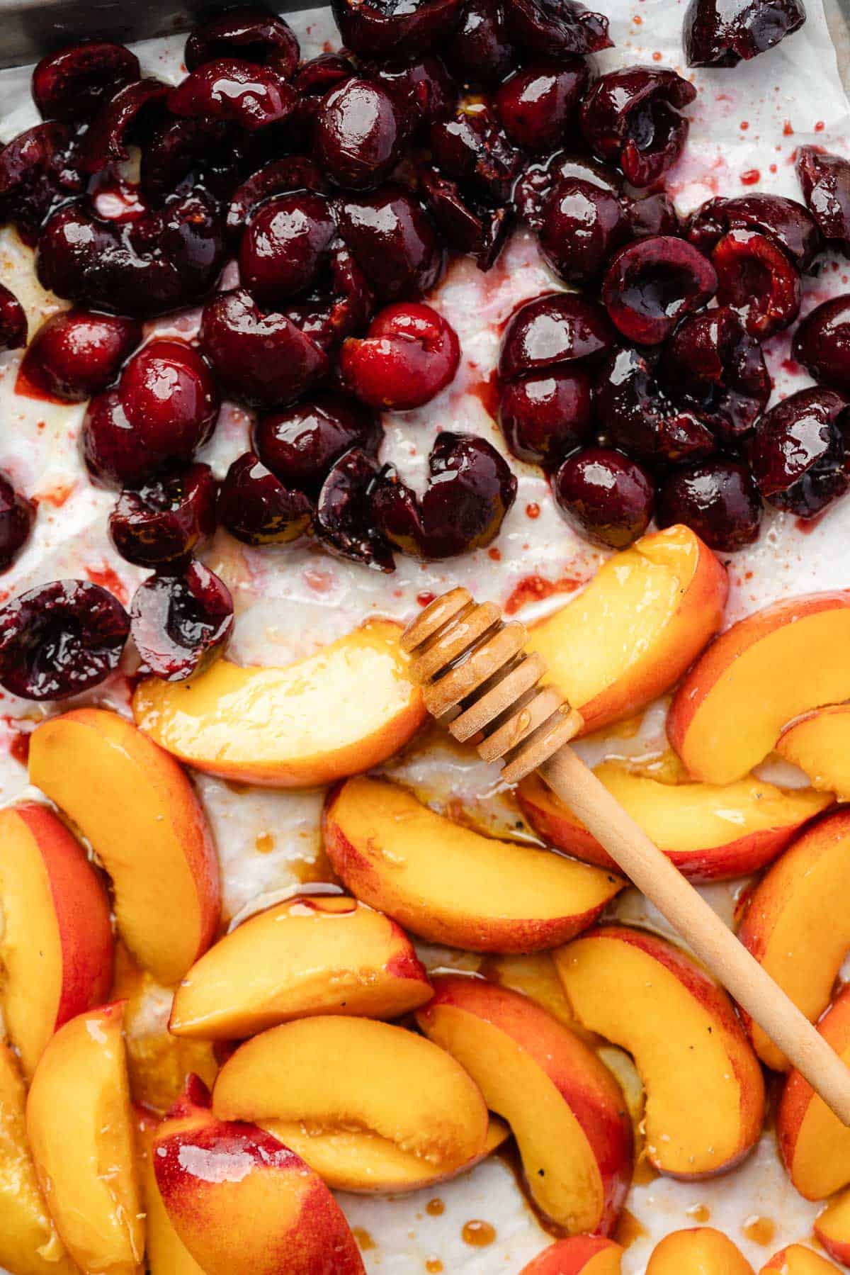 nectarines and cherries on parchment with balsamic vinegar and honey and a honey dropper