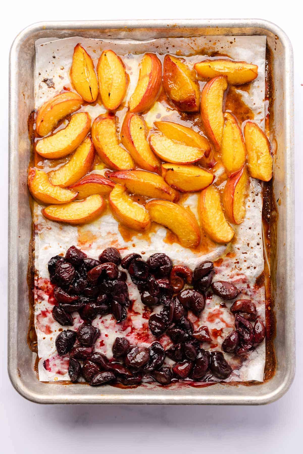 baked nectarines and cherries on a parchment lined baking sheet