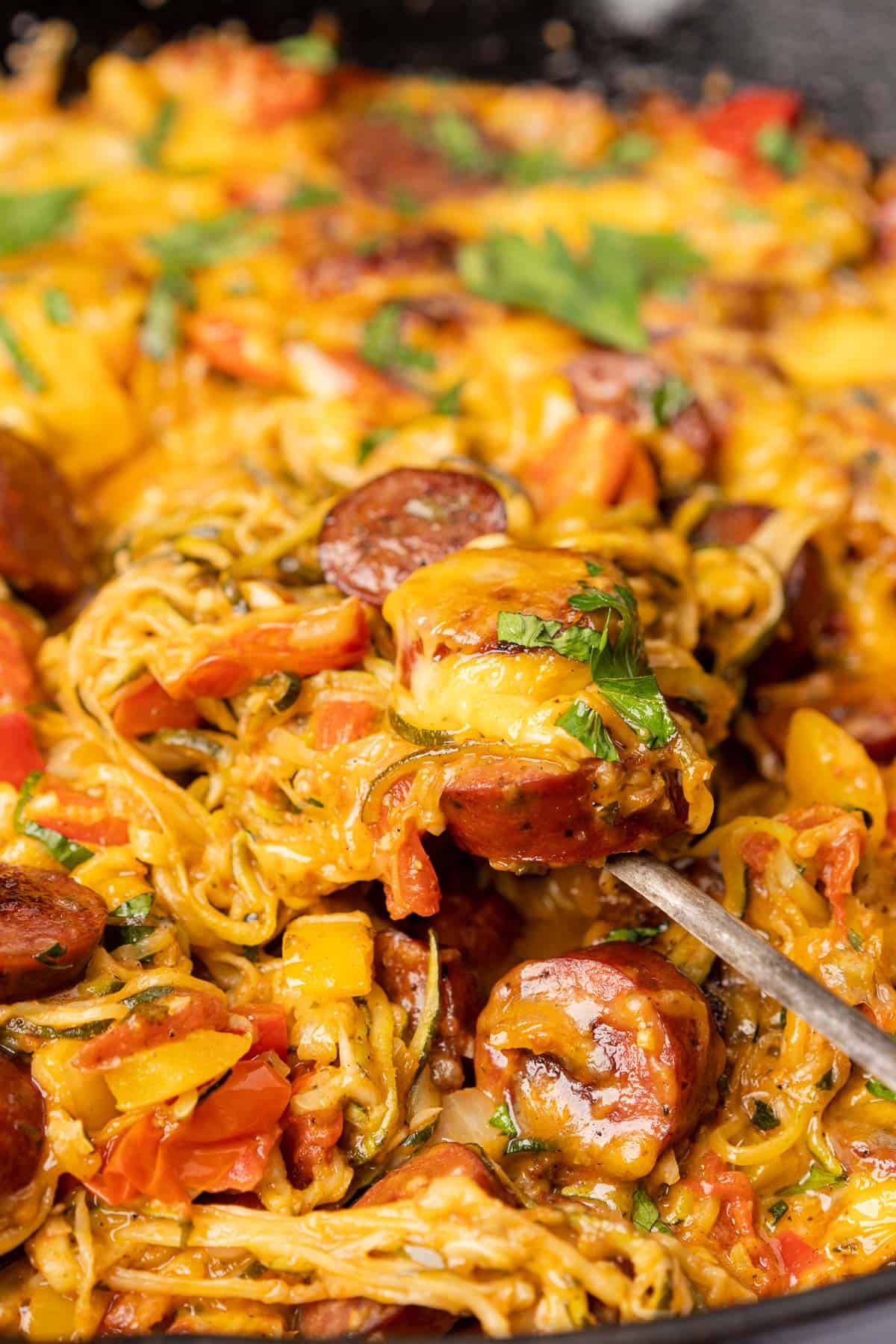 spoonful of cheesy baked zucchini noodles casserole with smoked sausage
