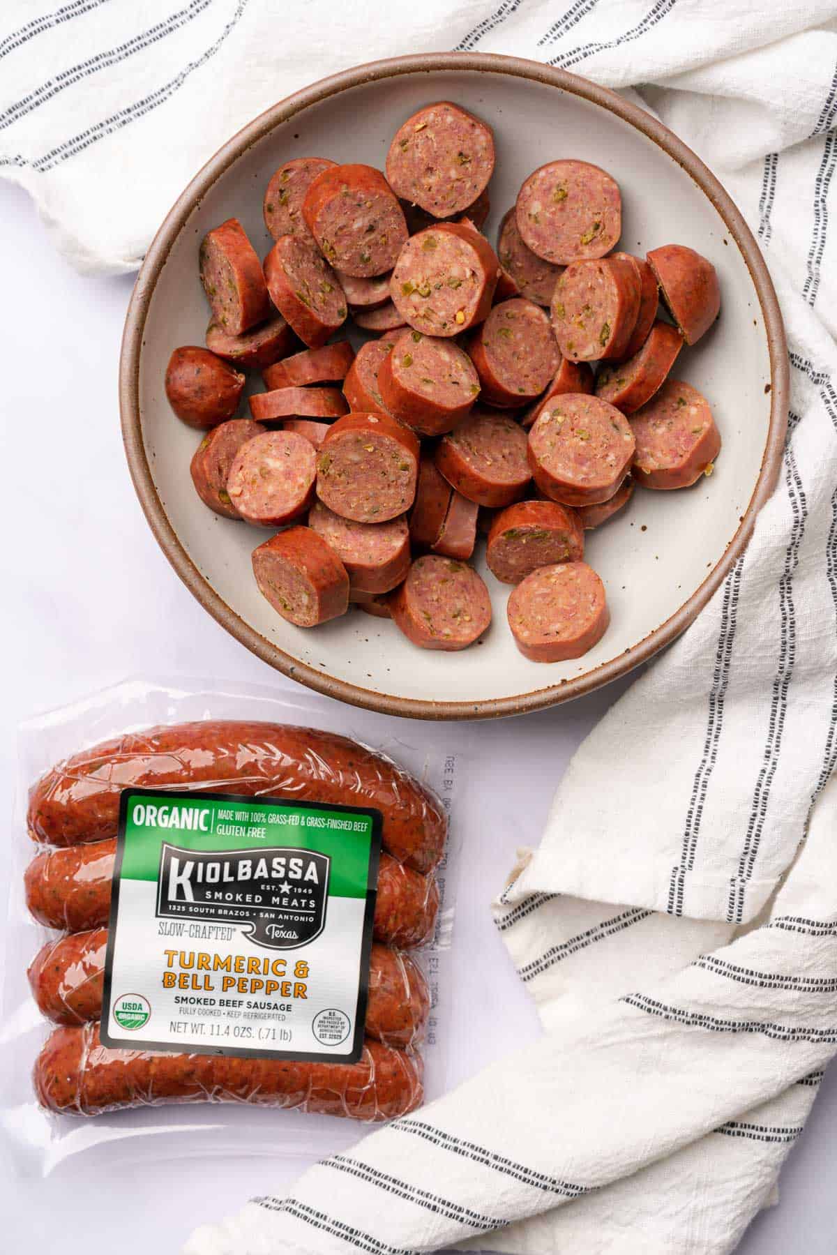 kiolbassa smoked meats turmeric and bell pepper organic beef sausage cut into rounds in a bowl, with a package beside it