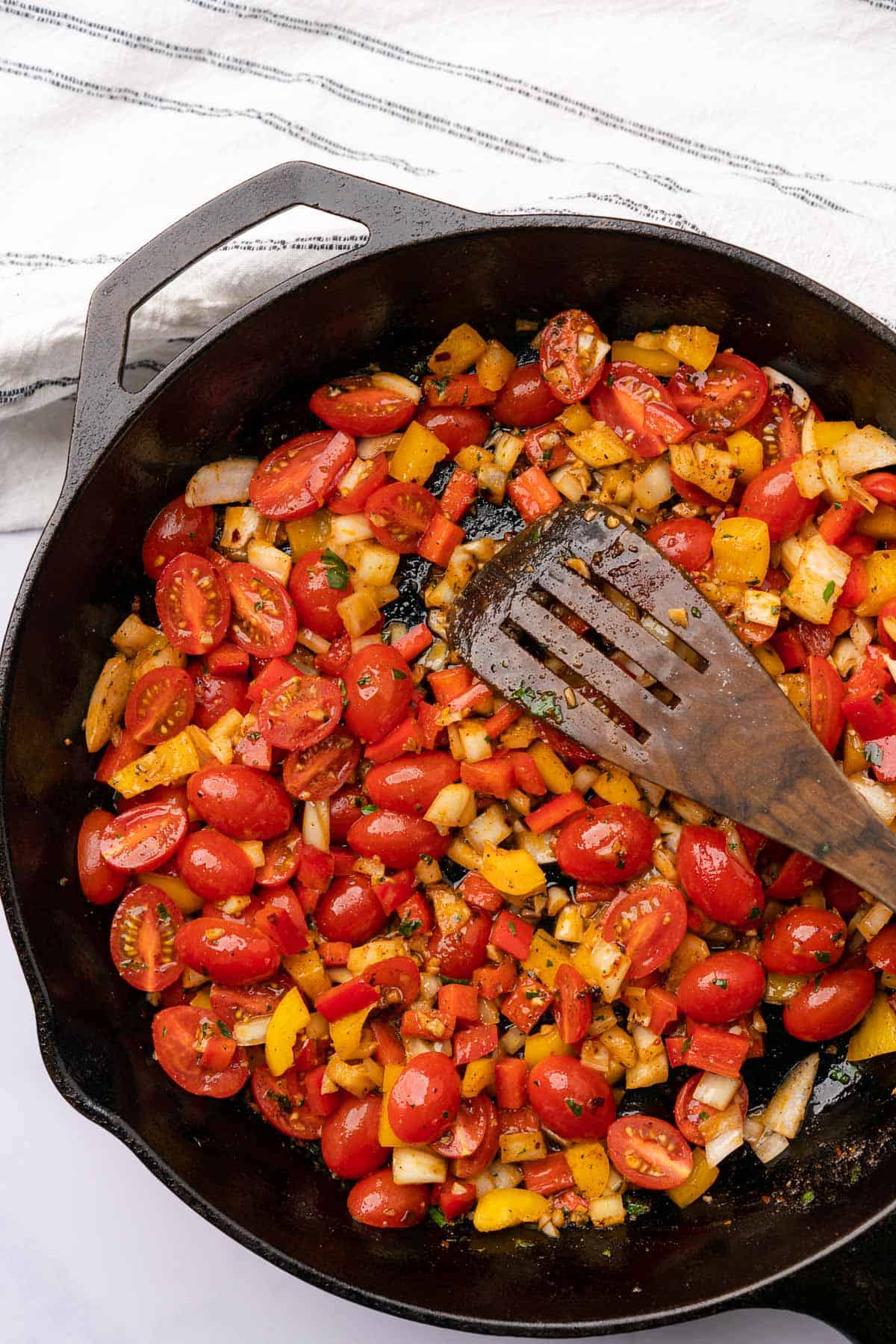 cast iron skillet with cherry tomatoes yellow and red bell peppers. and onions 