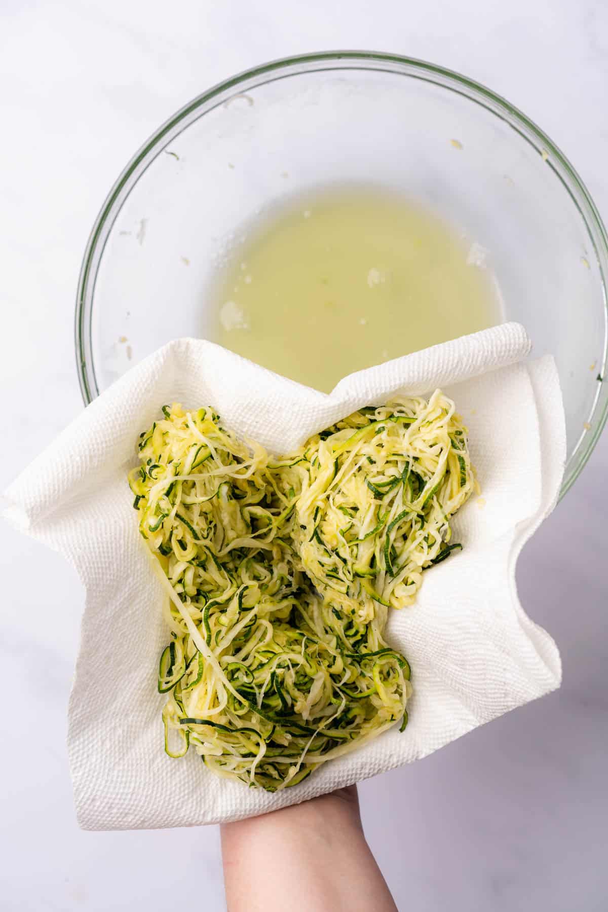 squeezing excess moisture out from zucchini noodles with paper towel
