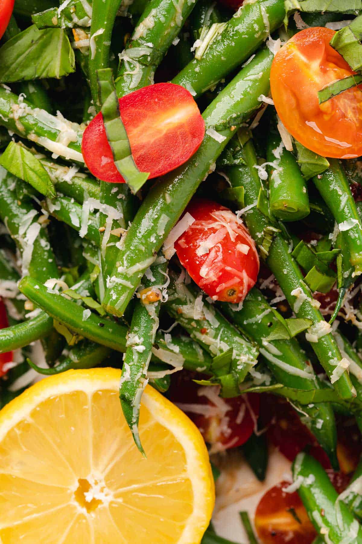 close up macro shot of Italian green bean salad with parmesan, lemon, tomatoes and basil