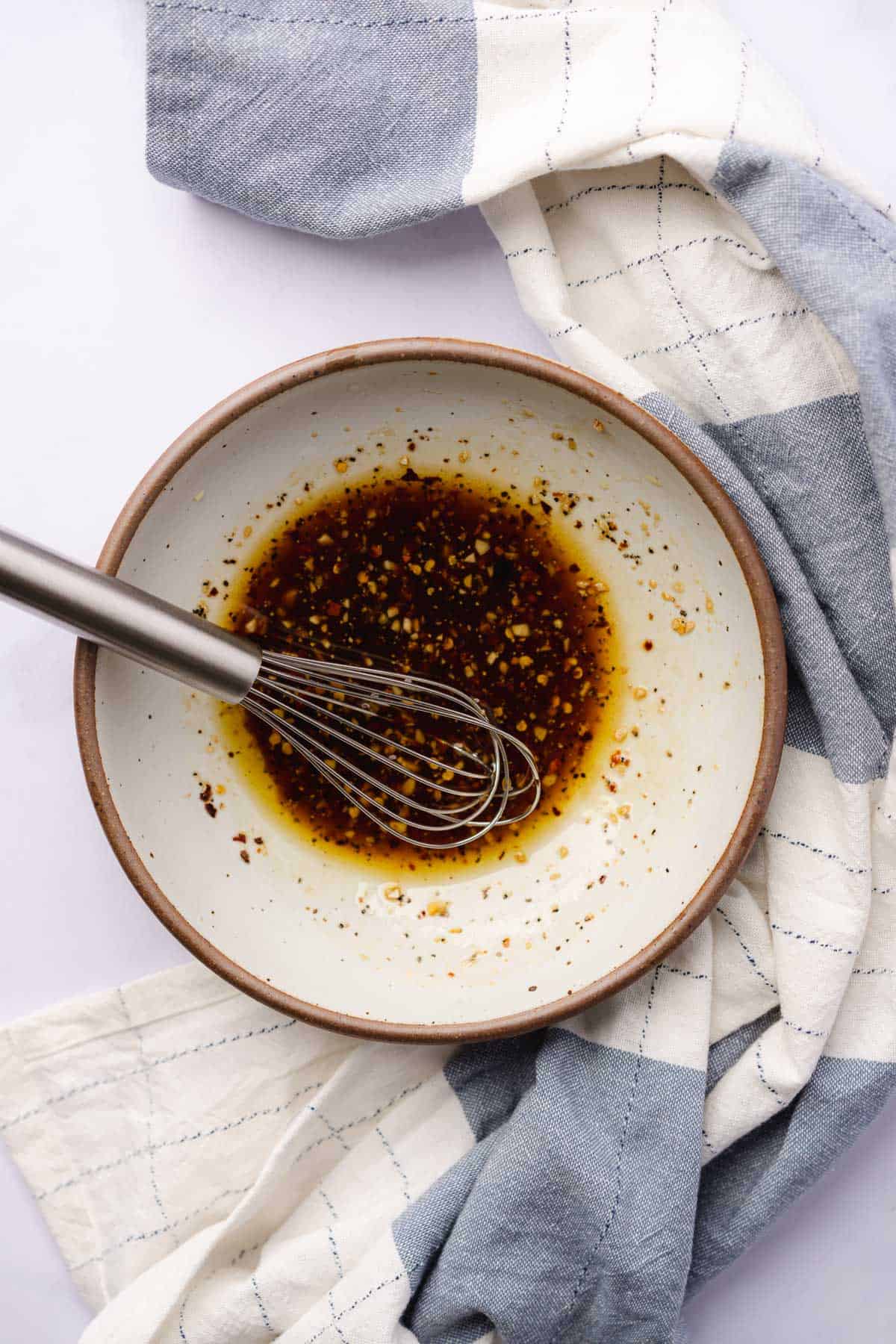 whisking together an olive oil and balsamic dressing for a salad