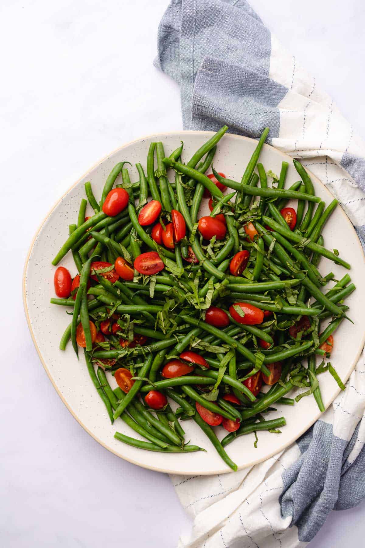 green beans and tomatoes on a large salad plate 