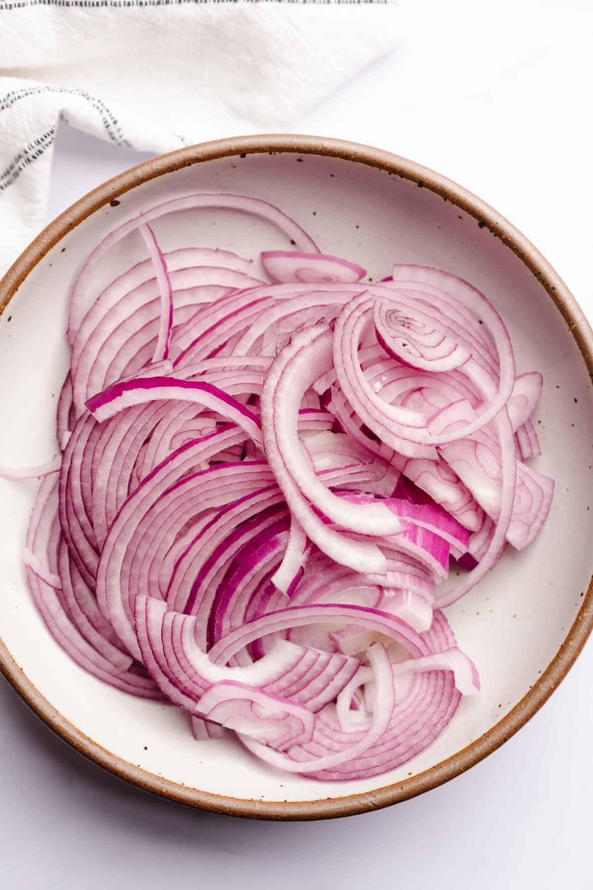 thinly sliced red onions in a bowl