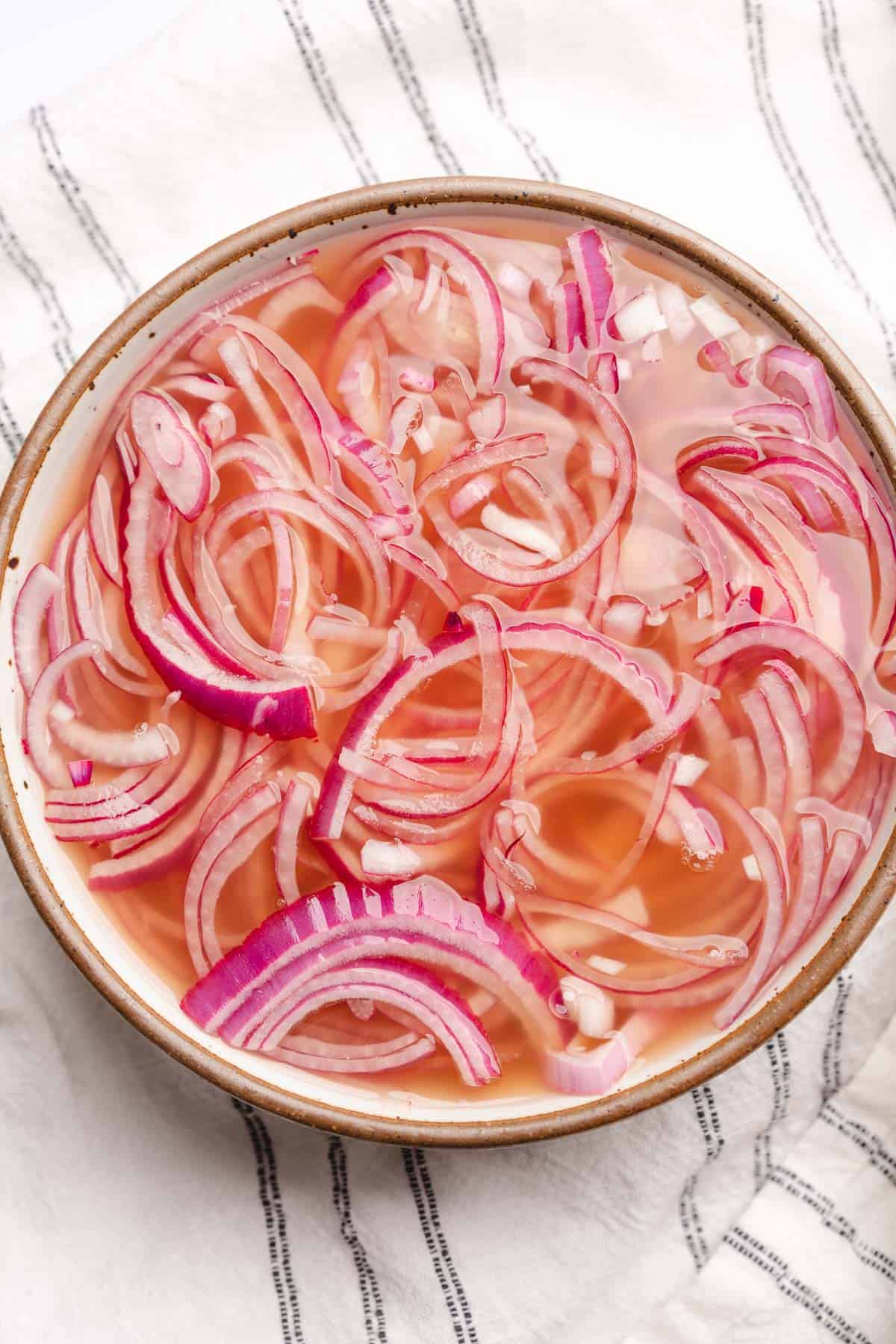 red onions in a large shallow bowl with pickling liquid