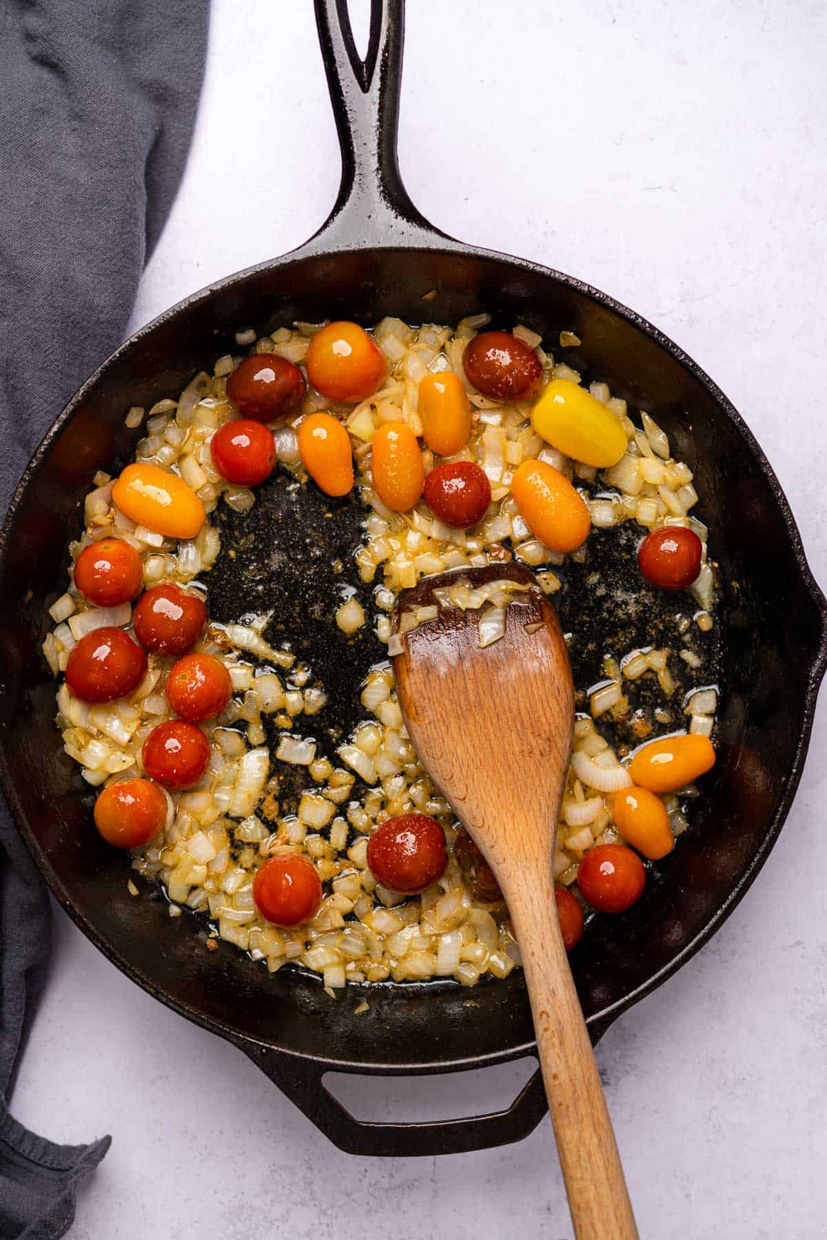 tomatoes and onions cooking in a cast iron skillet