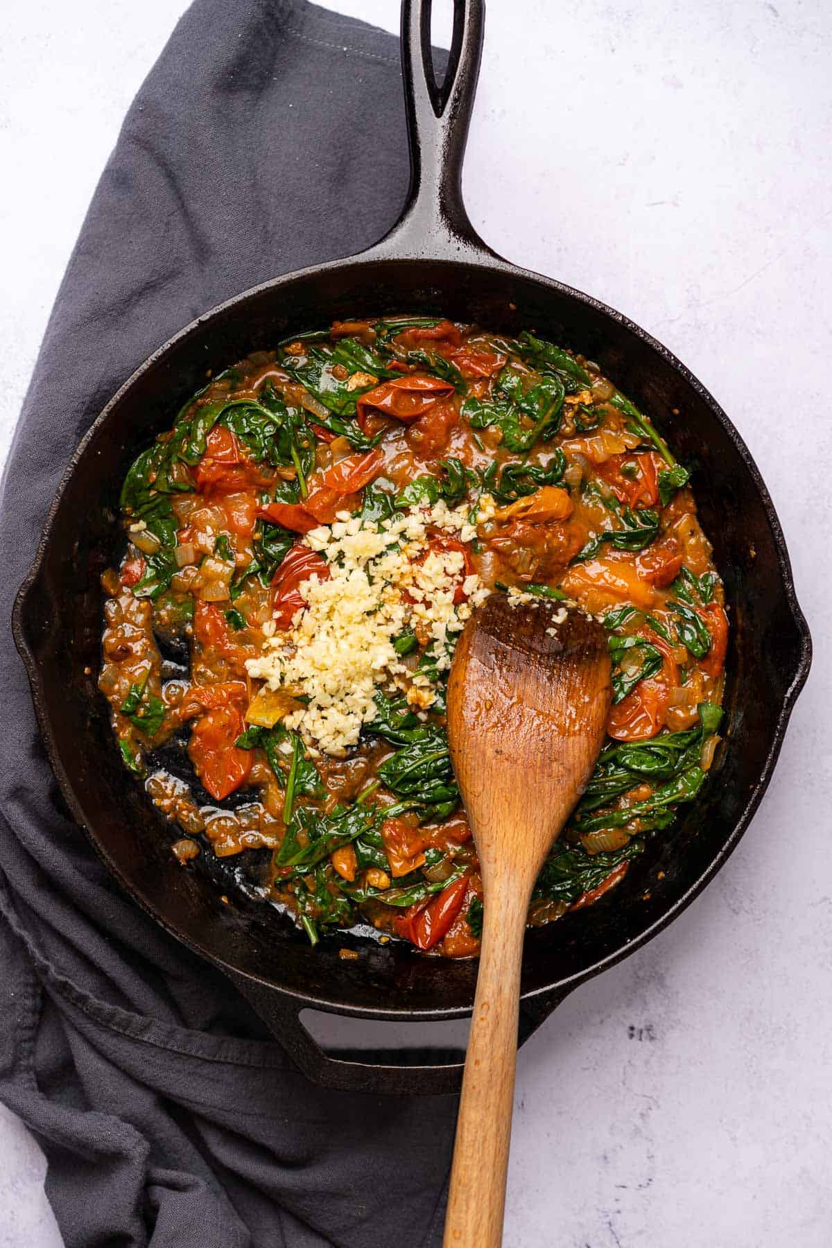 tomatoes spinach and garlic in a cast iron skillet