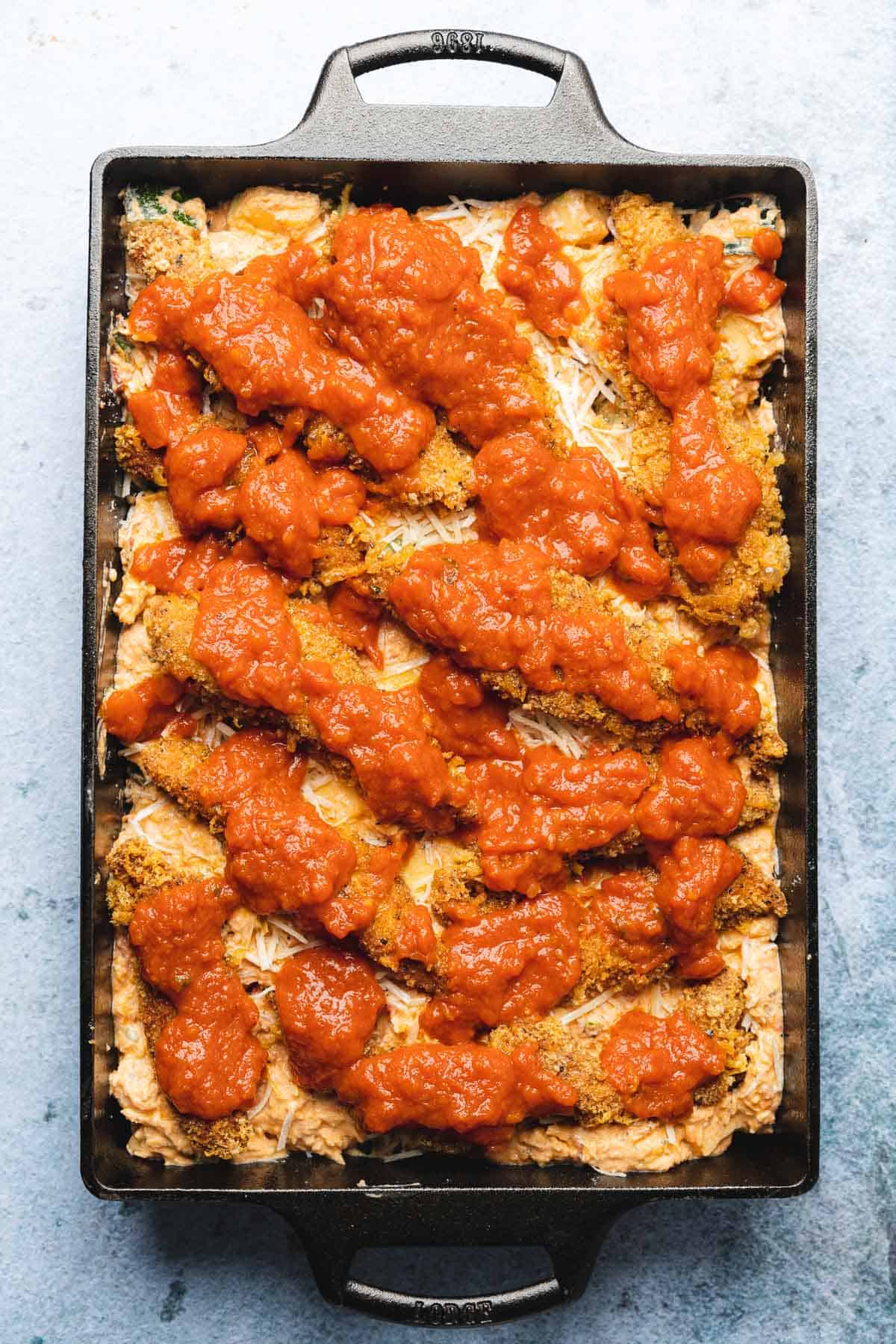 chicken parmesan tenders in a casserole dish covered with marinara sauce 