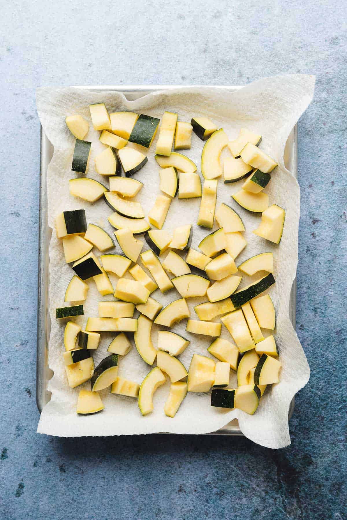 zucchini on a baking sheet with paper towels covered in salt