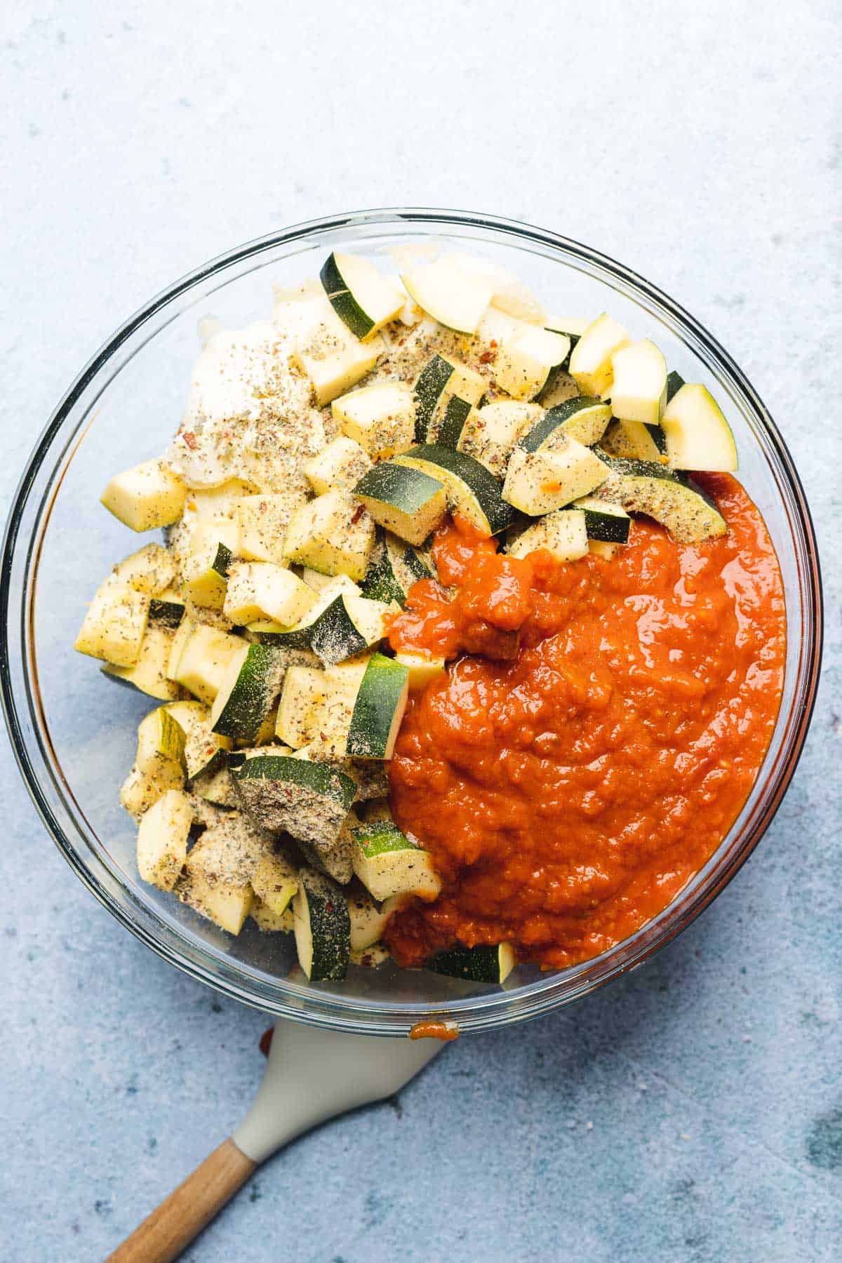 zucchini in a large bowl with marinara sauce 