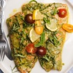 two gorgeous pesto butter salmon fillets with tomatoes basil and lemons