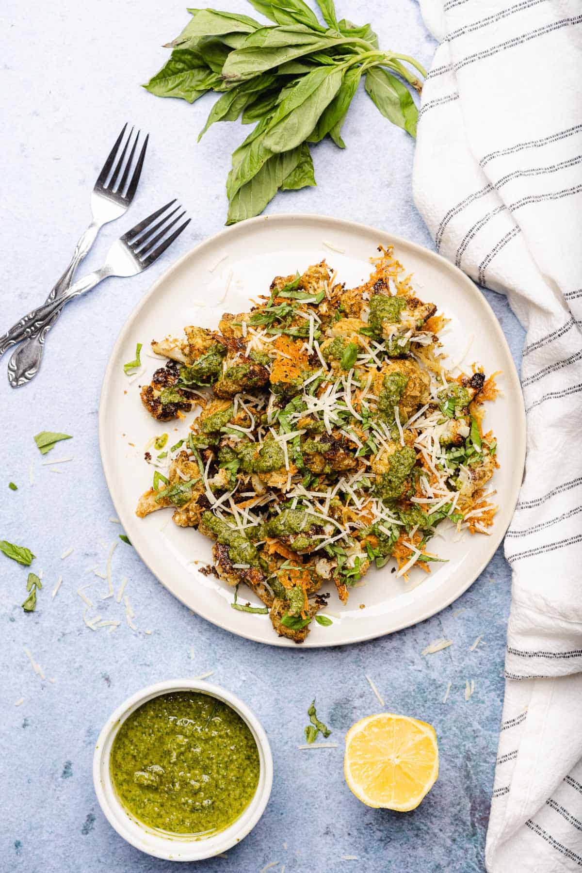 crispy pesto cauliflower with parmesan cheese on a plate on a blue backdrop
