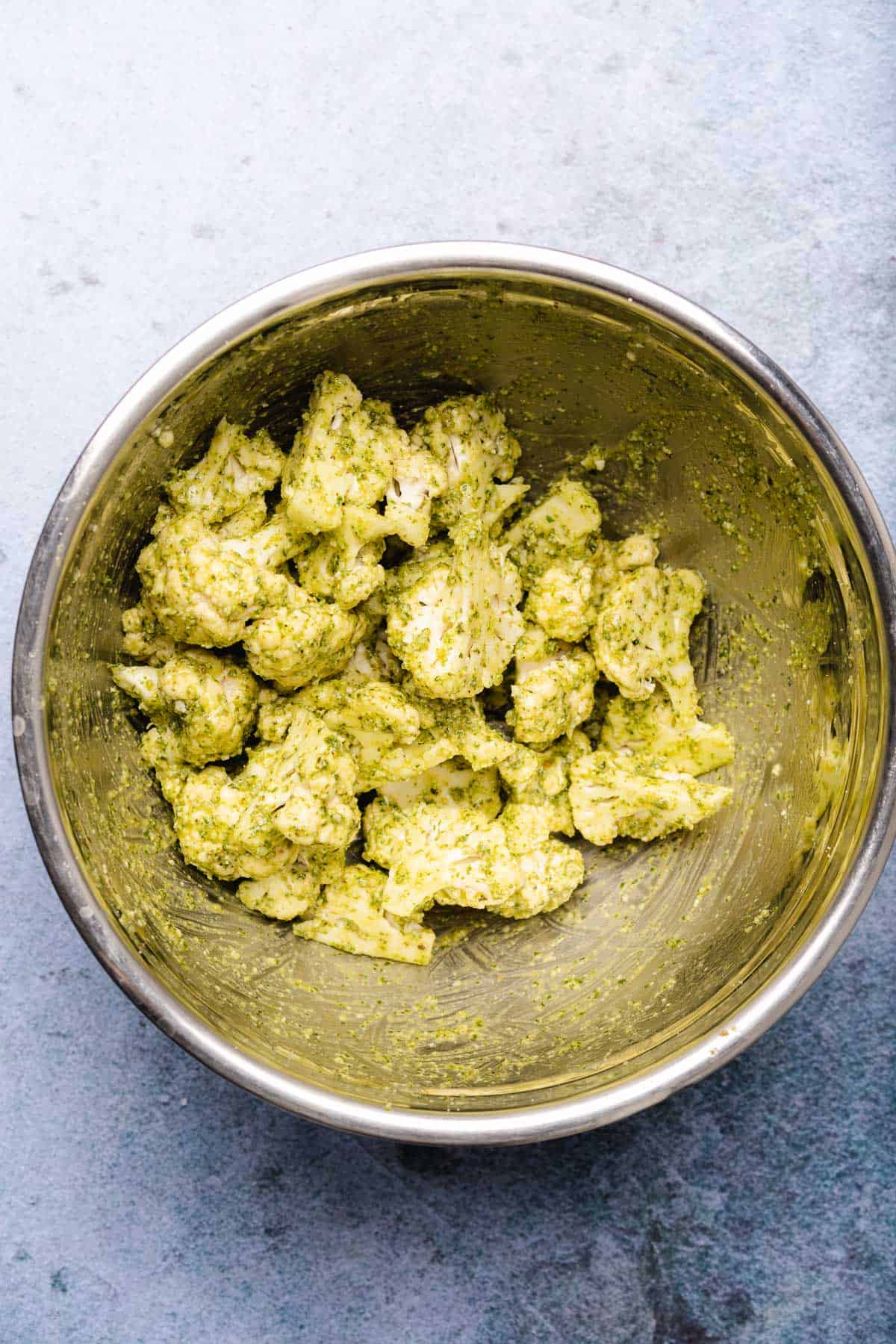 cauliflower florets in a bowl coated with pesto