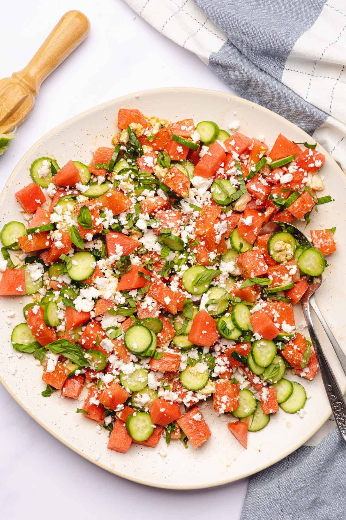 close up shot of a watermelon cucumber salad with feta cheese and fresh herbs