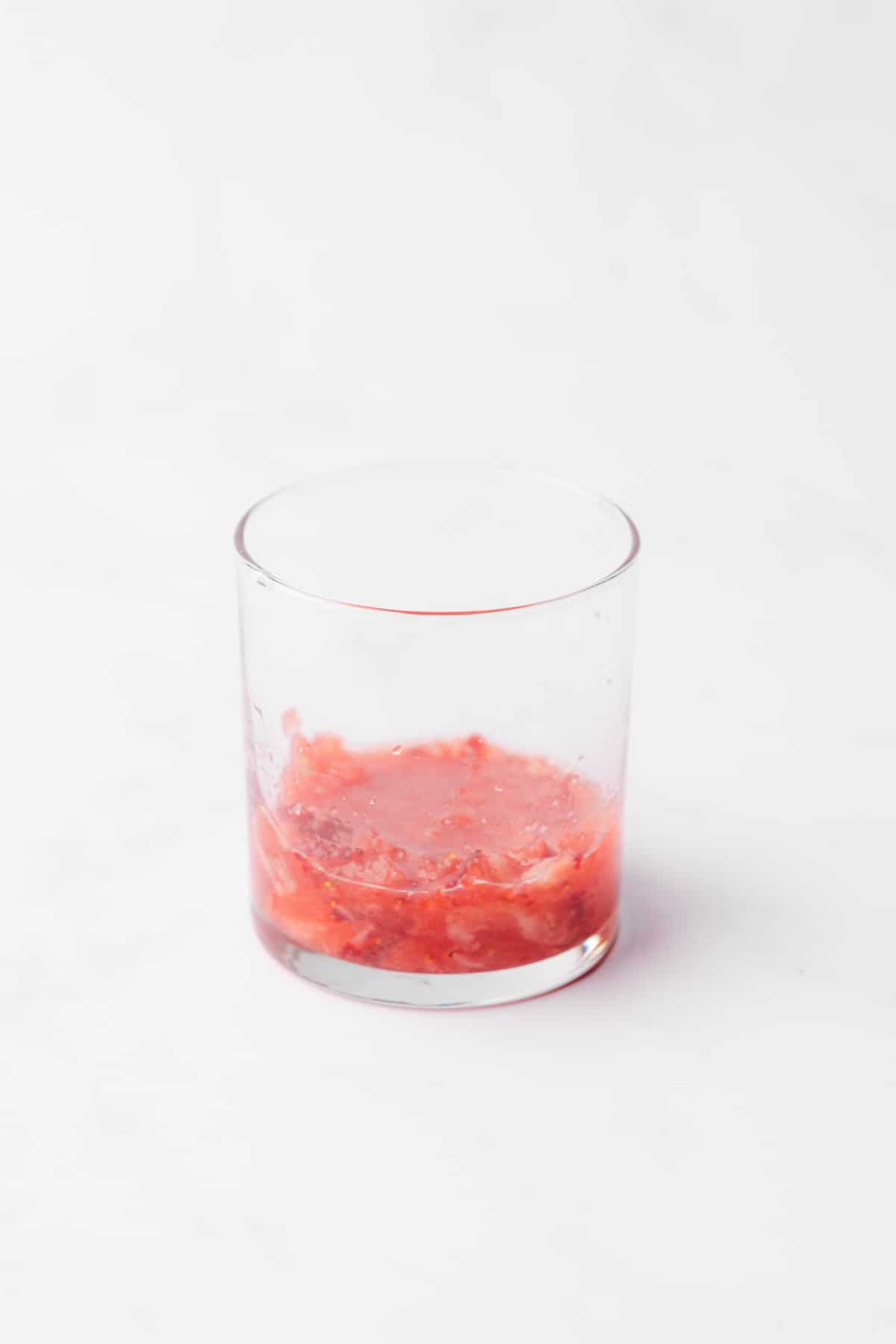 muddled watermelon and strawberry in the bottom of a glass