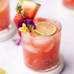 45 degree shot of a watermelon wine cooler with lime and edible flowers