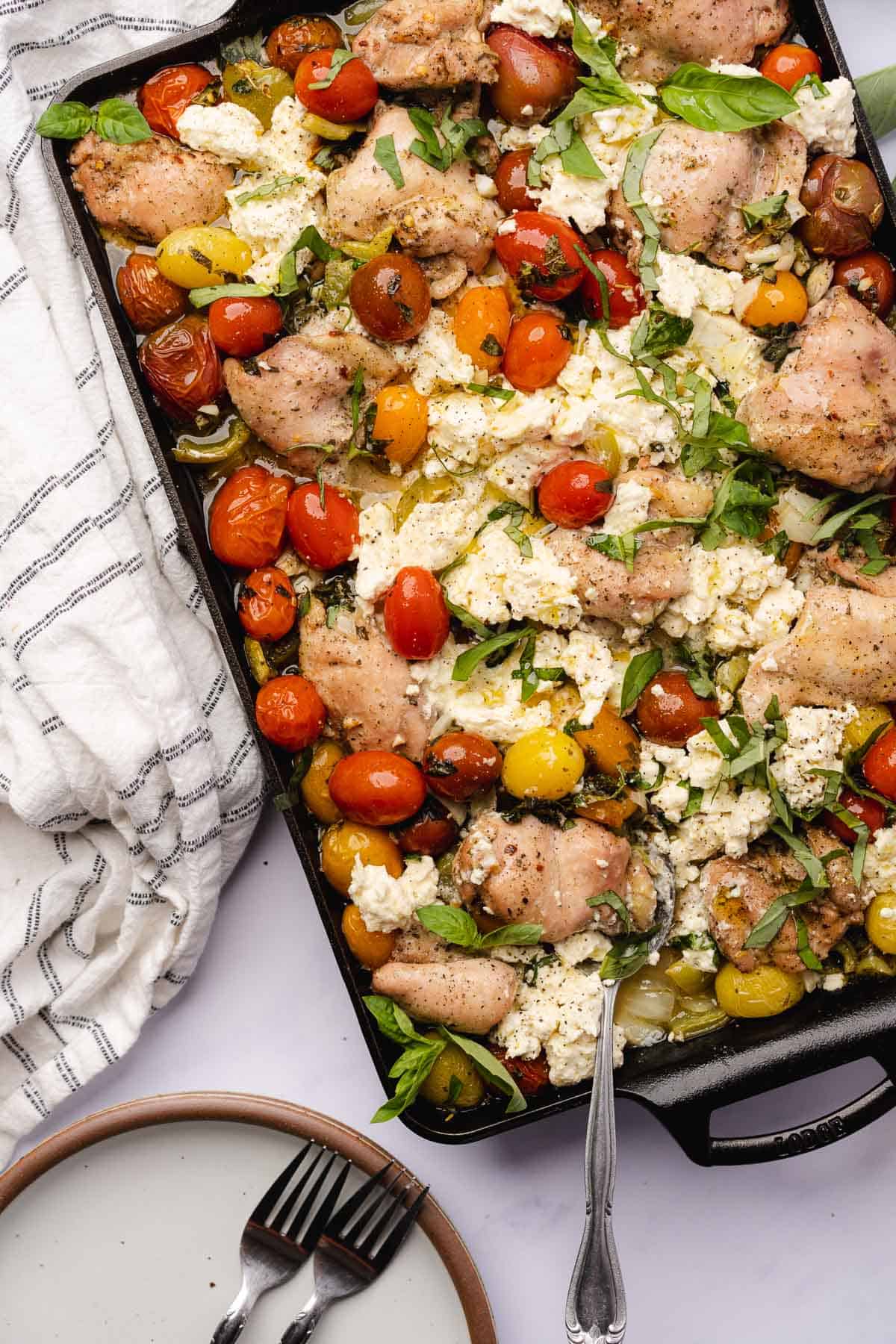 close up shot of baked chicken feta sheet pan dinner with veggies and herbs