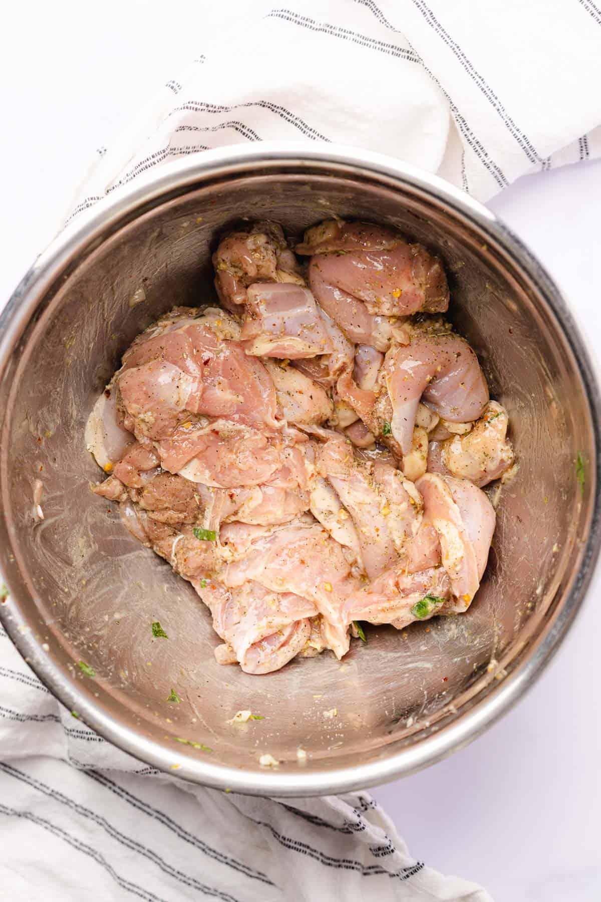 raw chicken thighs in a bowl with seasoning