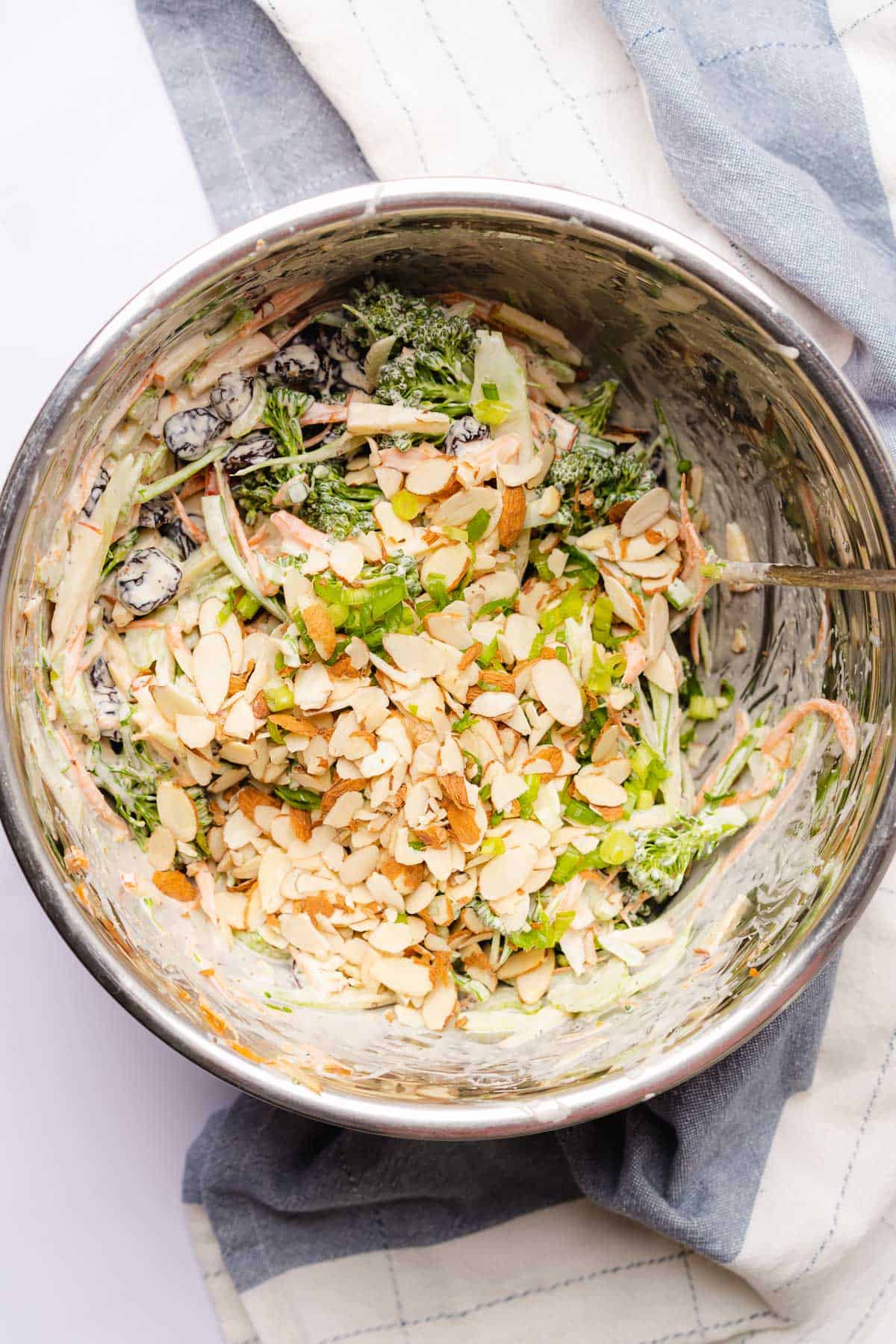 green onions and almonds to broccolini slaw in a bowl