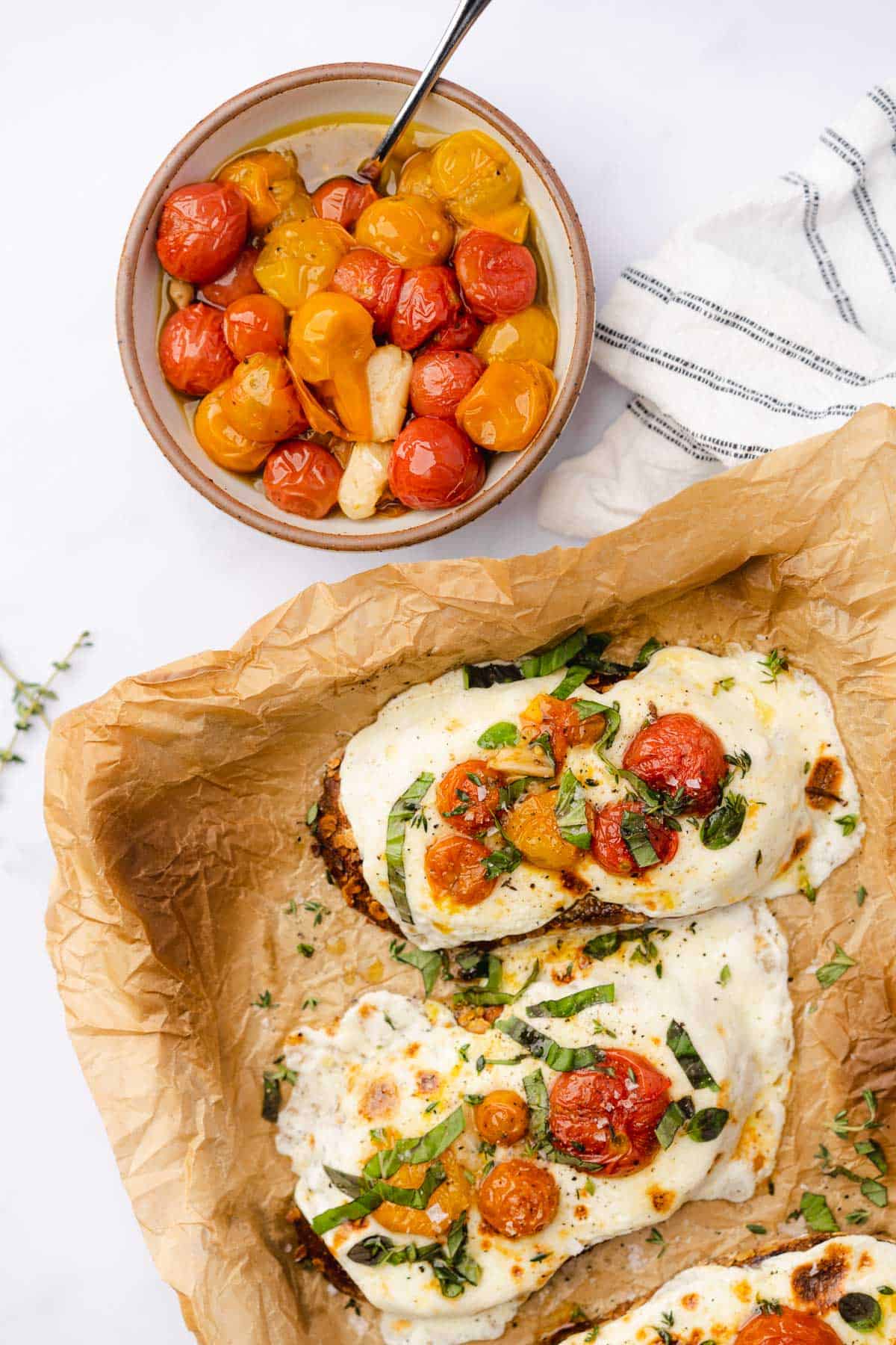 cheesy toast on a parchment lined baking sheet with cherry tomato confit