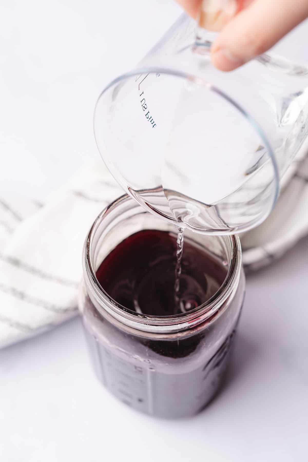 pouring vodka into a container of sweetener blackberry liqueur