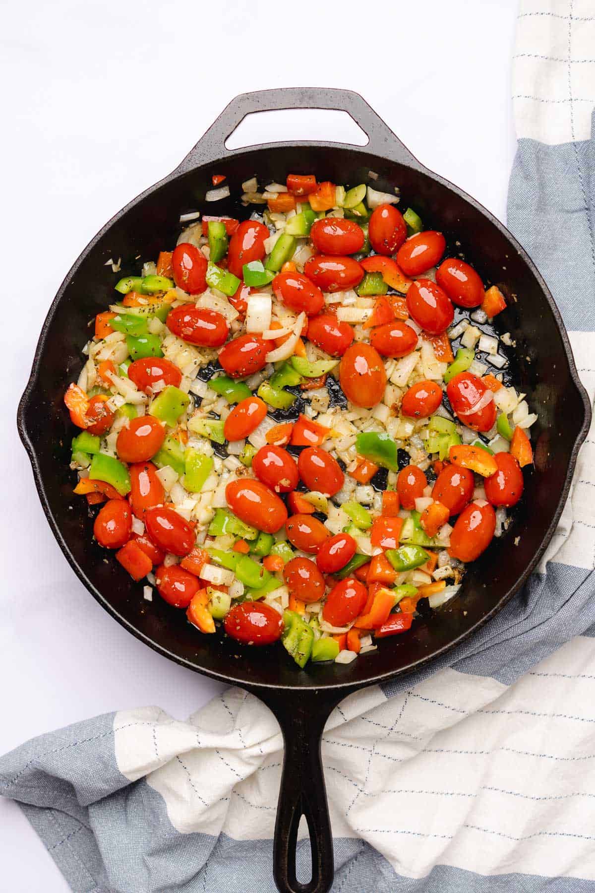 tomatoes, bell peppers, and onion in a cast iron skillet