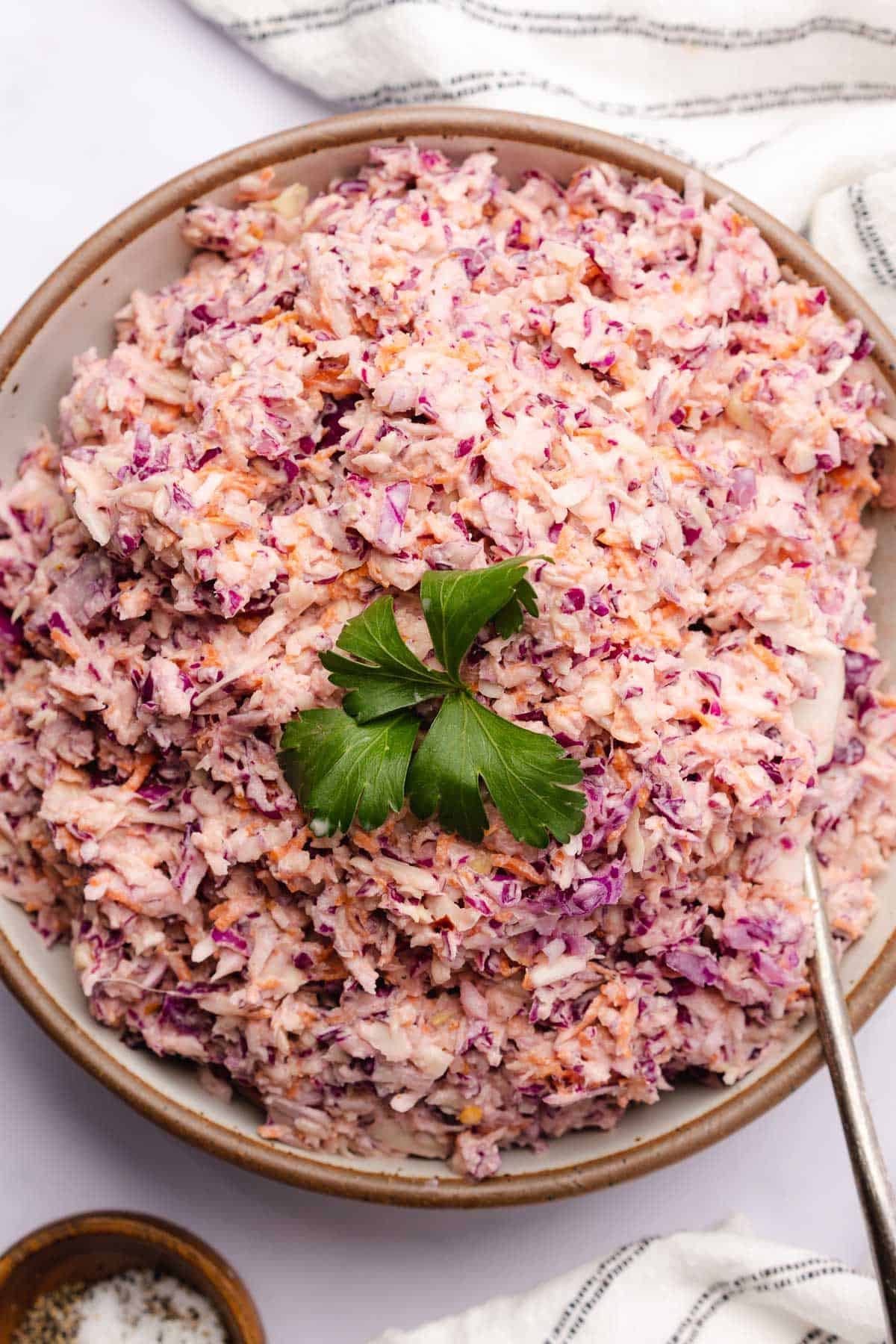 coleslaw mixed in a bowl topped with parsley 