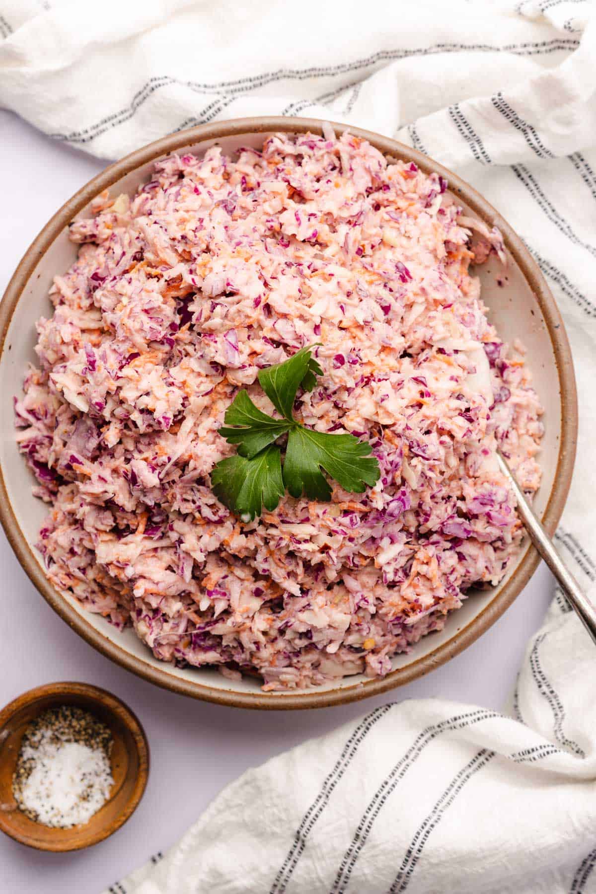 keto coleslaw topped with parsley in a ceramic bowl with a spoon