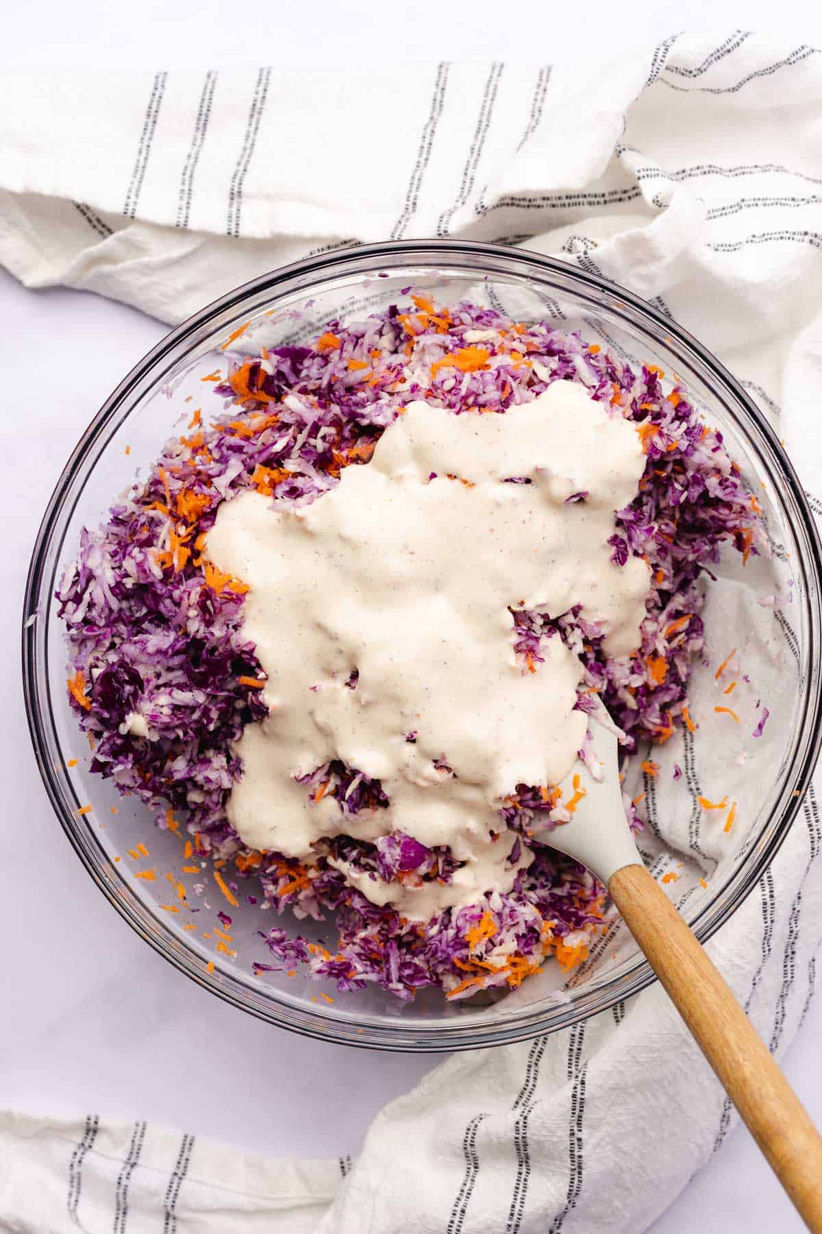 coleslaw mixture in a large glass bowl with mayo dressing on top 