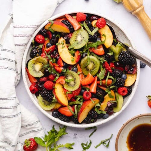 keto fruit salad surrounded by fresh herbs and balsamic vinegar