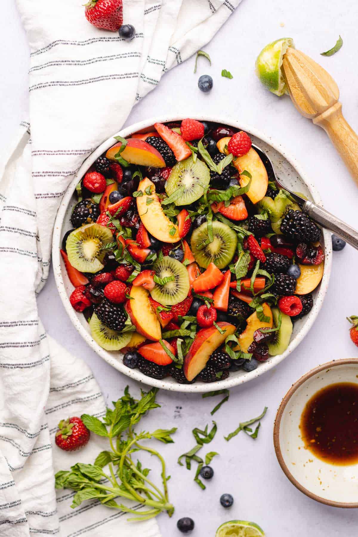 keto fruit salad surrounded by fresh herbs and balsamic vinegar