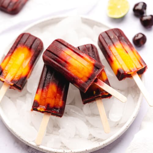 mango cherry popsicles with lime on a plate with ice