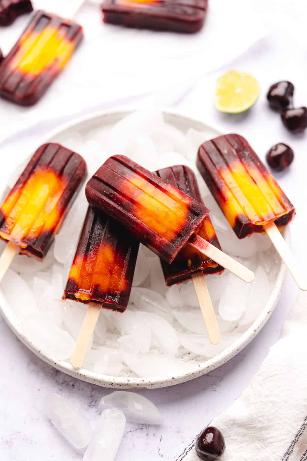 mango cherry popsicles with lime on a plate with ice