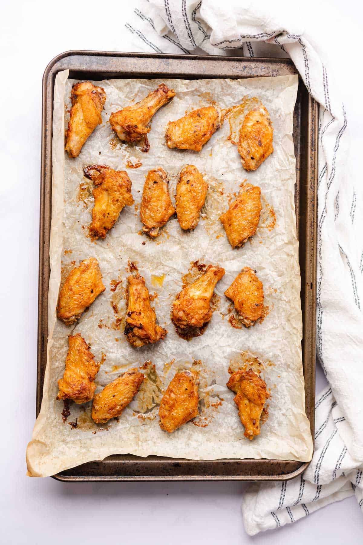 crispy chicken wings baked on a parchment lined baking sheet 