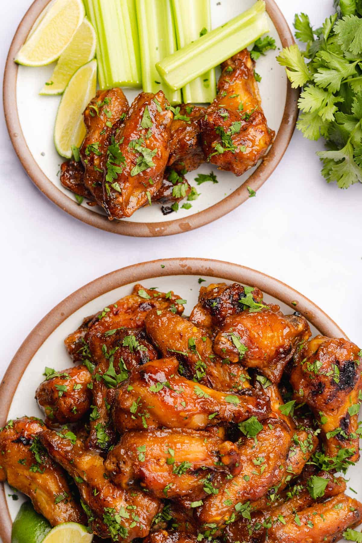 plate of mango chicken wings with celery, cilantro and limes