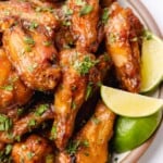 close up shot of mango habanero wings with lime wedges and cilantro