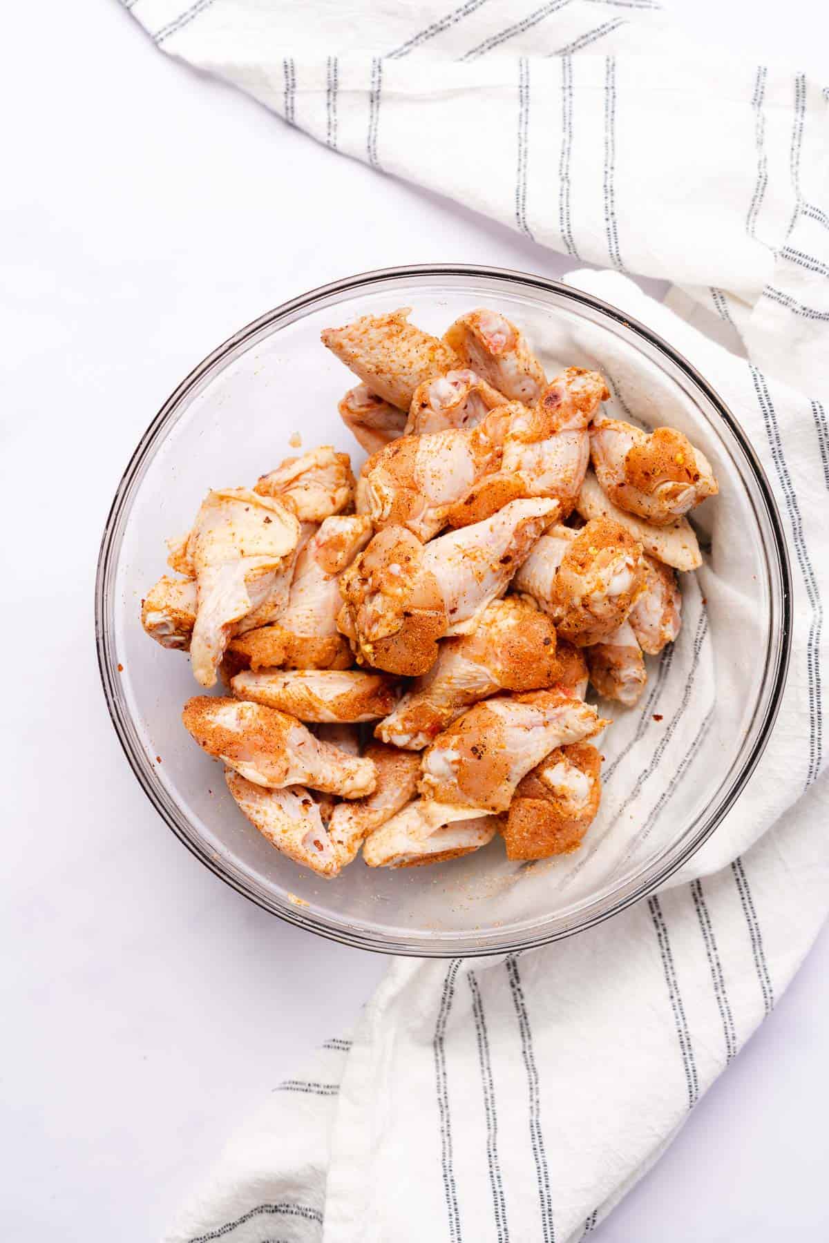 raw chicken wings ina. bowl with seasonings