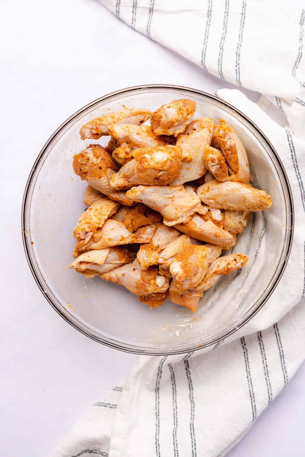 chicken wings tossed in a bowl ready to be baked