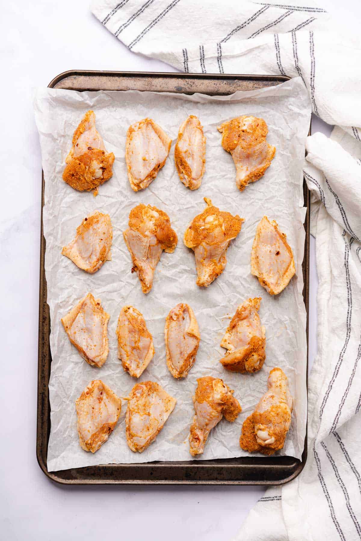 raw chicken wings seasoned and placed on a parchment lined baking sheet 