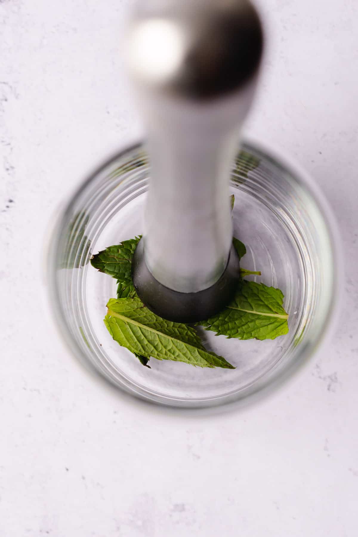 muddling mint in the bottom of a cocktail glass