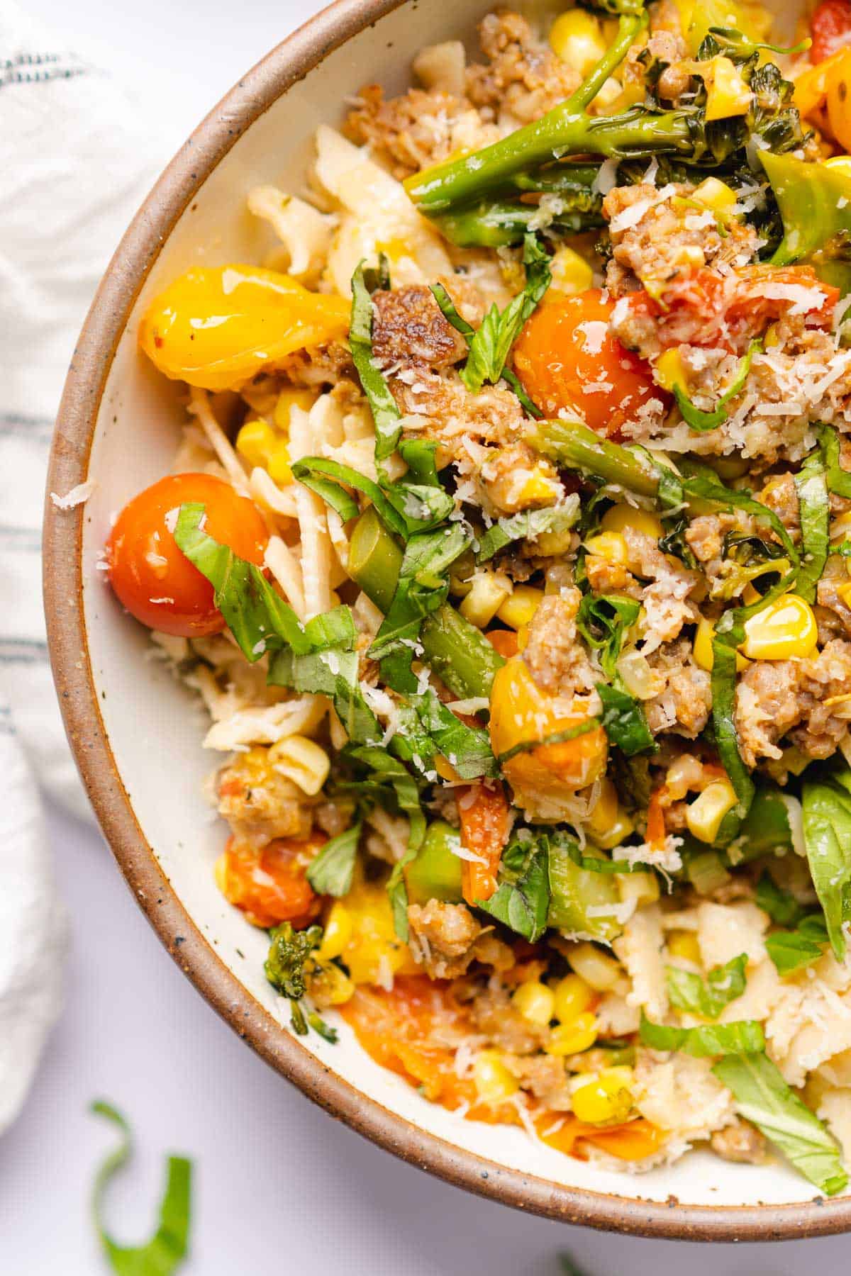 lovely close up shot of a bowl of sausage broccolini pasta with corn and tomatoes 