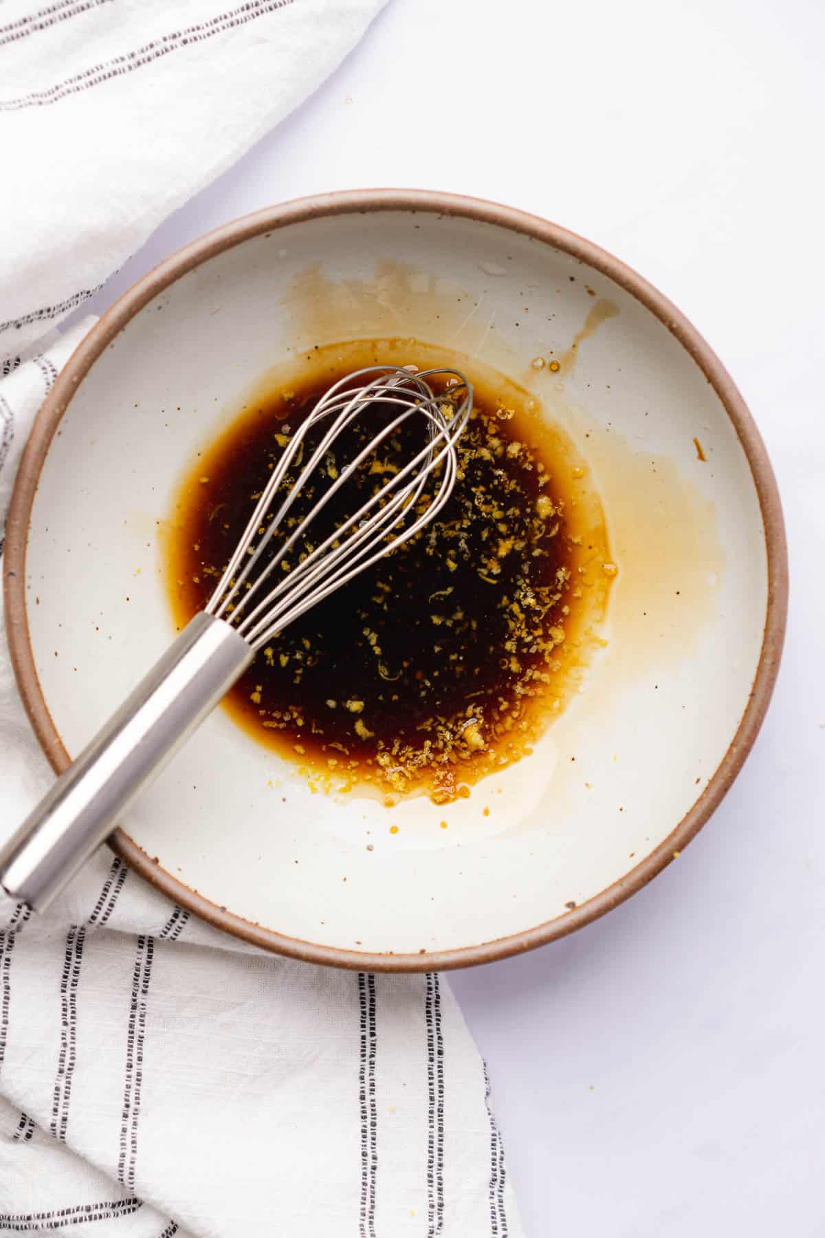 whisking together ingredients to make a dressing of balsamic vinegar, lemon juice and zest