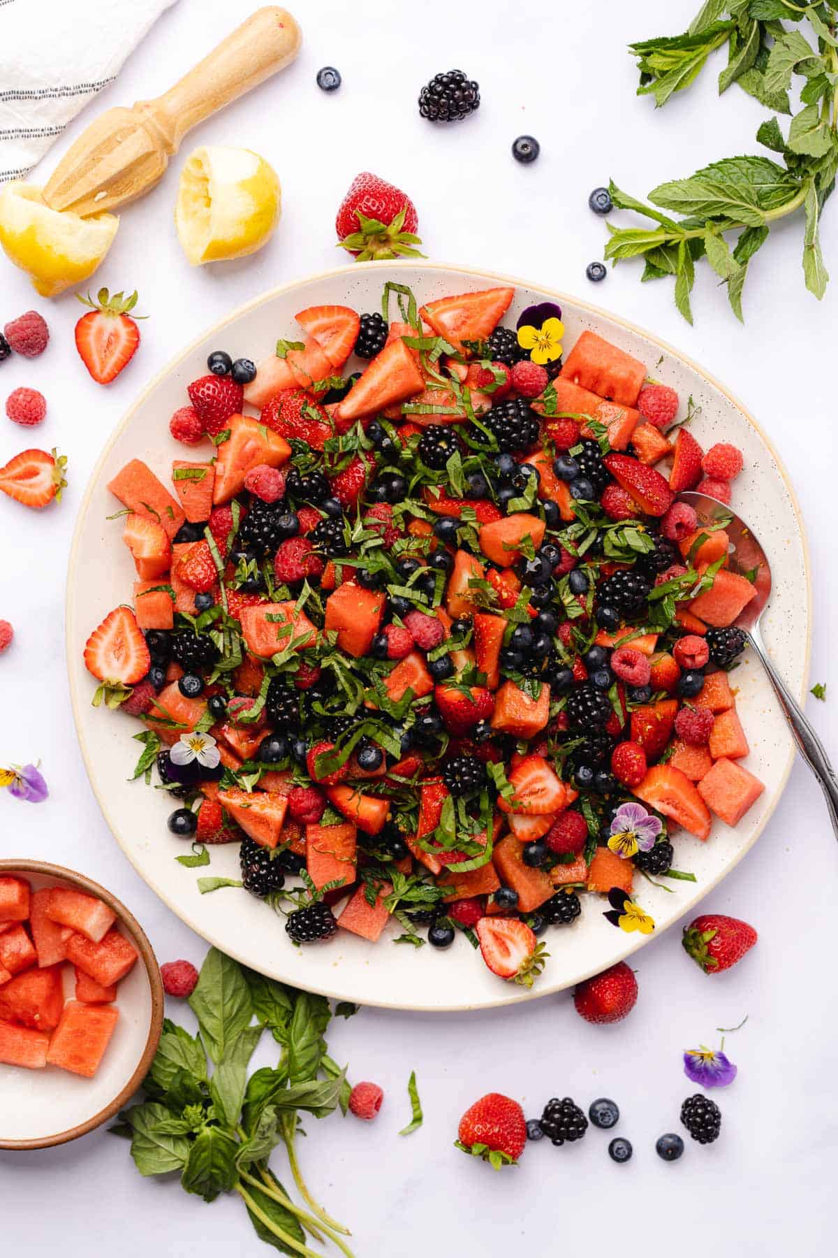 beautifully designed watermelon berry salad with fresh herbs, lemon juice and edible flowers