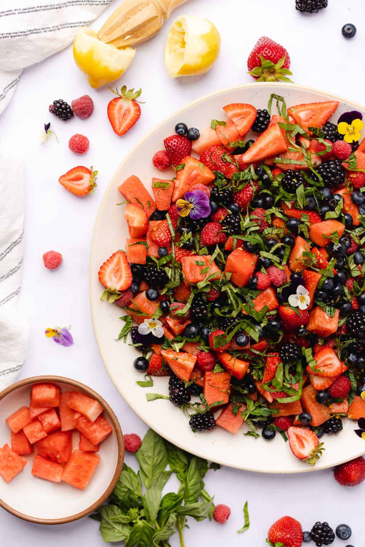 stunning display of watermelon and berries on a platter with edible flowers